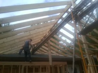Rafters going up over a new addition with a worker on the wall in Brookings