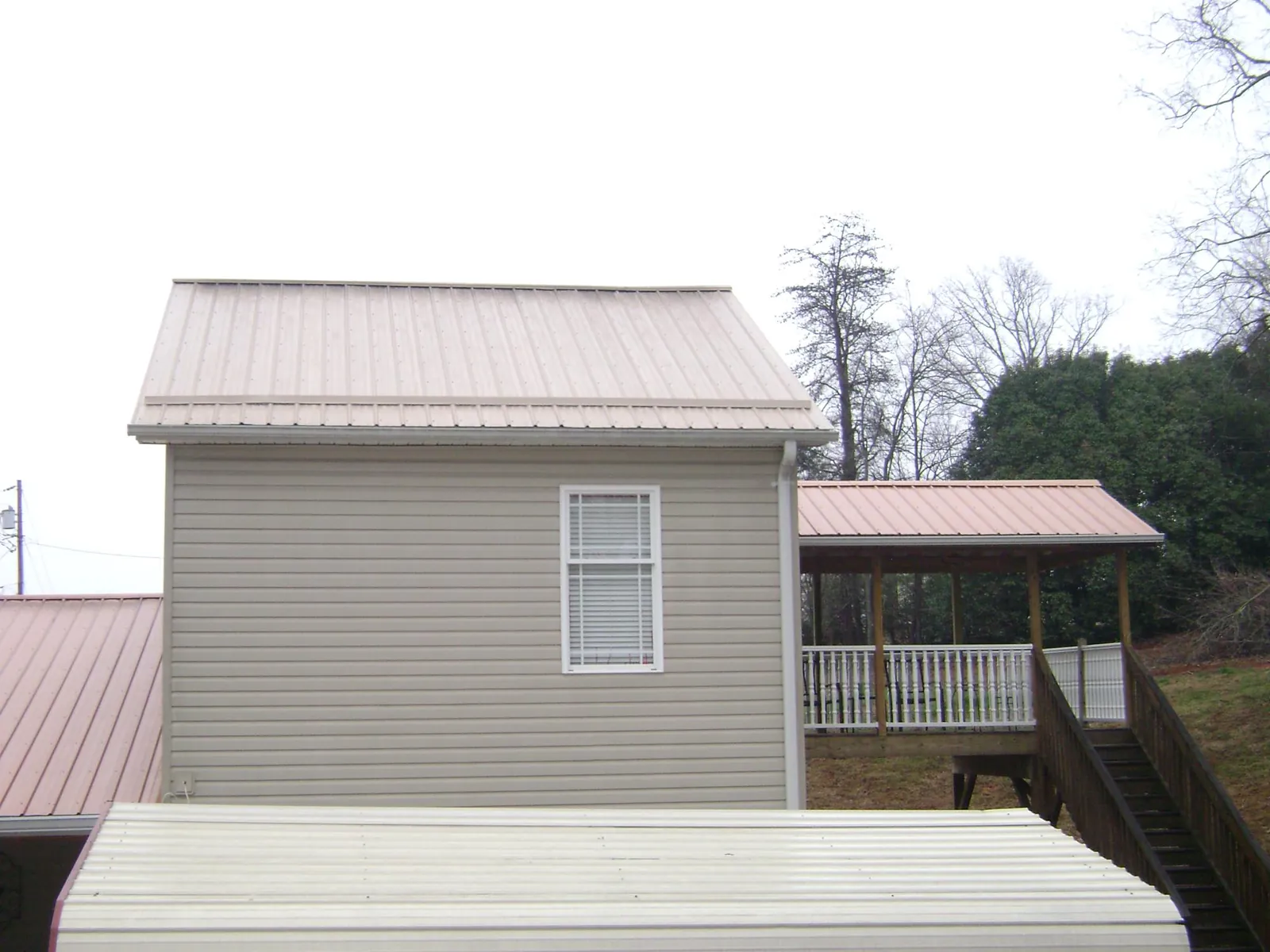 Tan metal roofs on a two story addition and attached porch, from a Roof Replacement job in Brookings